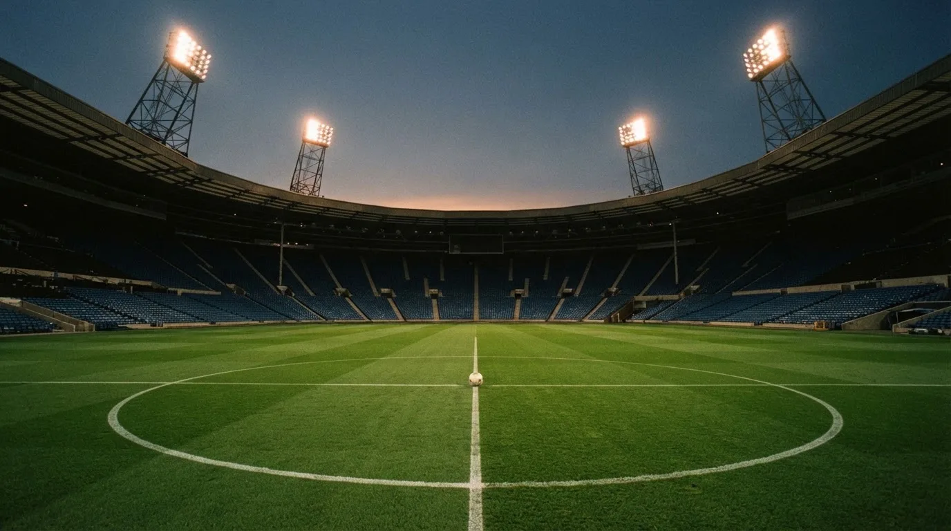 Een leeg voetbalstadion met lichtmasten bij schemering