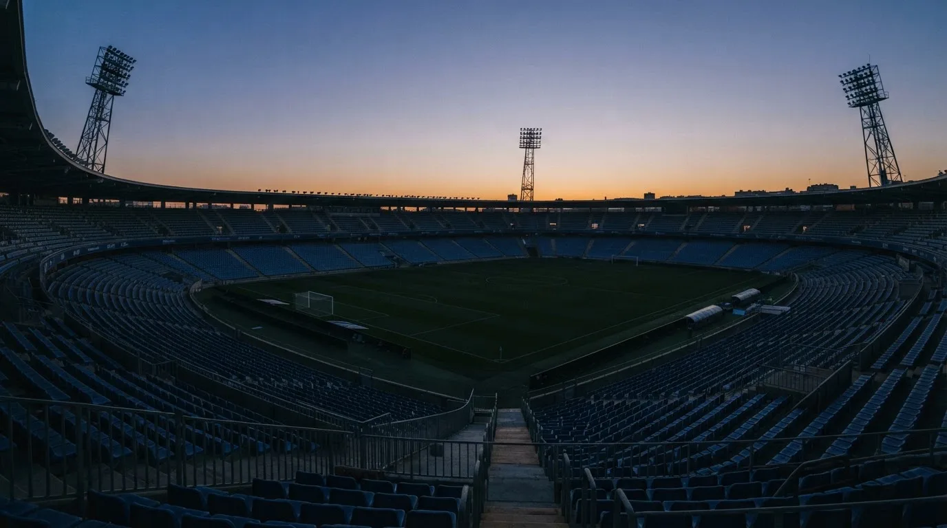 Een leeg voetbalstadion met lichtmasten bij schemering