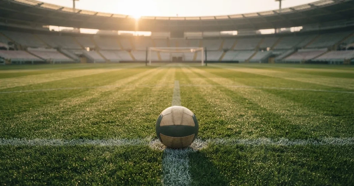Een voetbal op de middenstip van een grasveld in het ochtendlicht