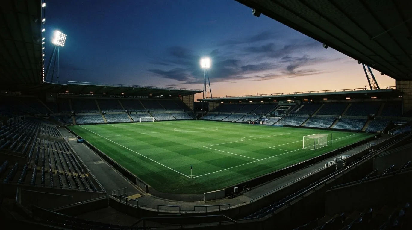 Een leeg voetbalstadion met lichtmasten bij schemering