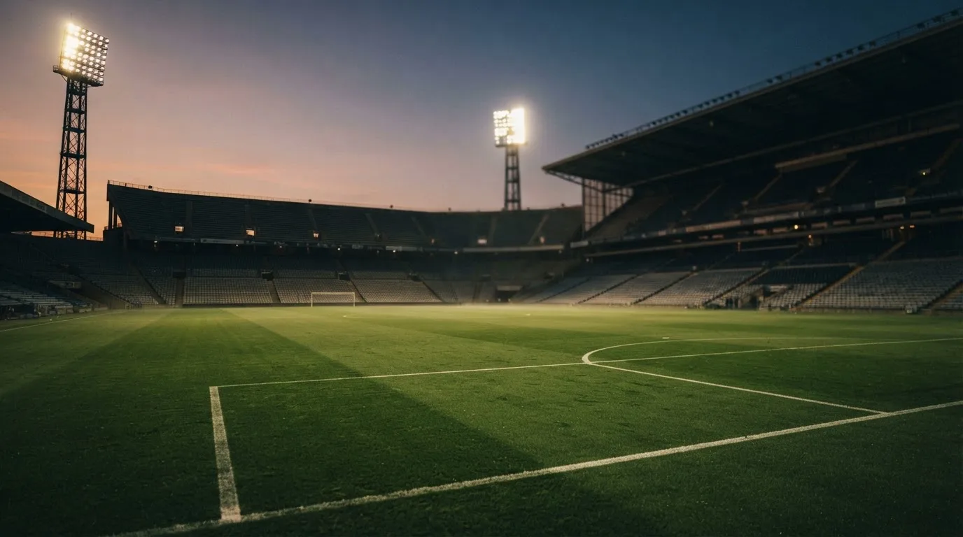 Een leeg voetbalstadion met lichtmasten bij schemering