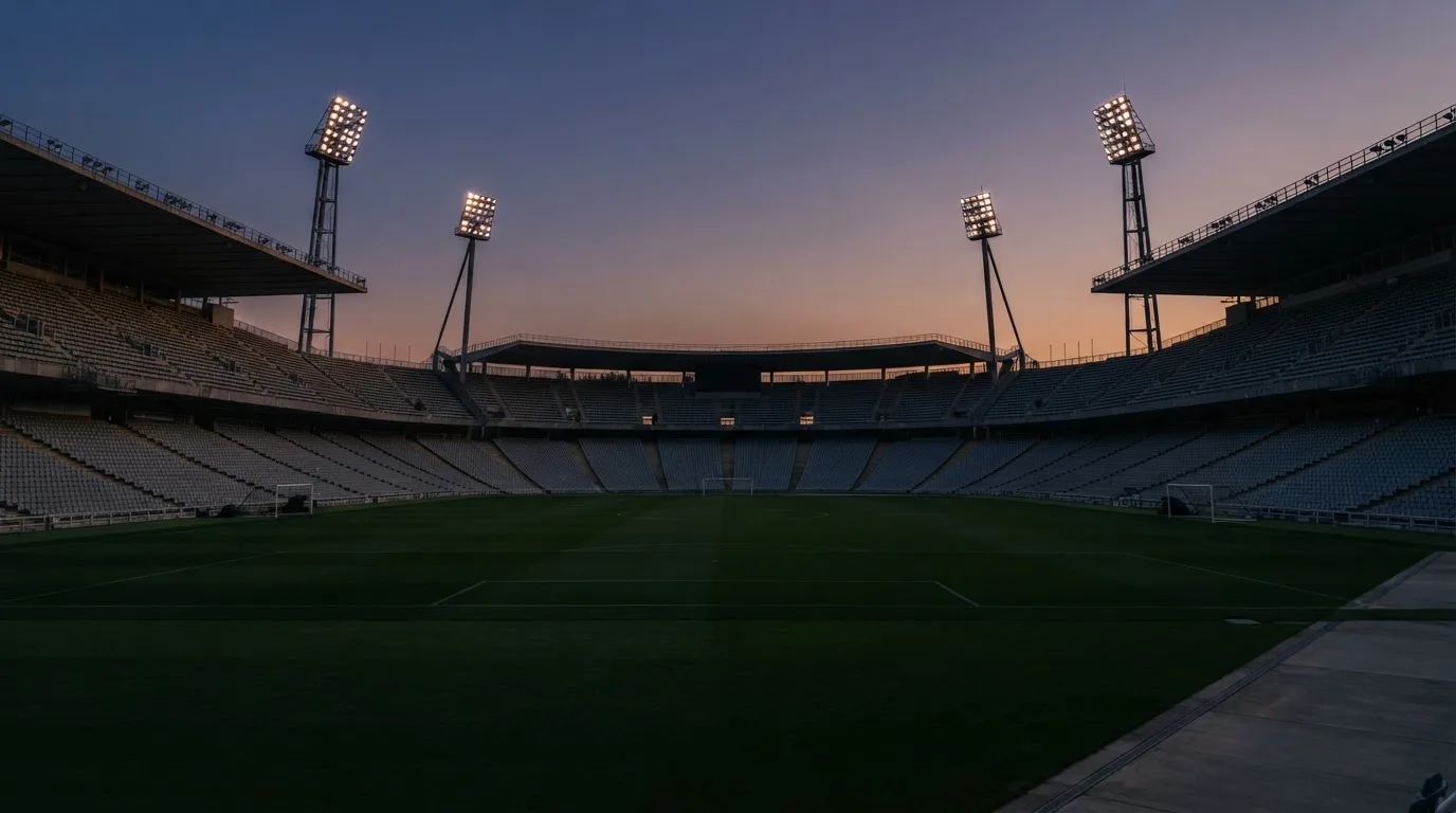 Een leeg voetbalstadion met lichtmasten bij schemering