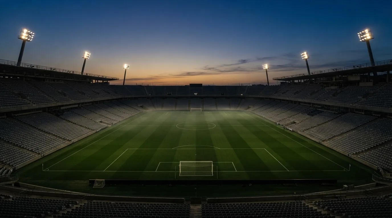 Een leeg voetbalstadion met lichtmasten bij schemering