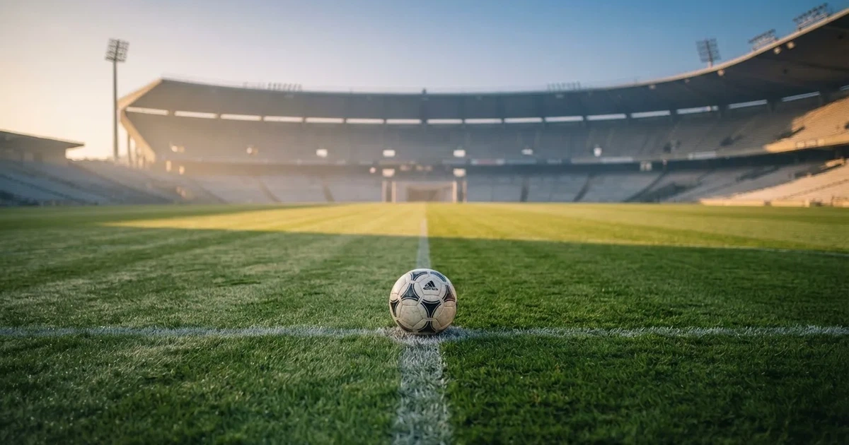 Een voetbal op de middenstip van een grasveld in het ochtendlicht
