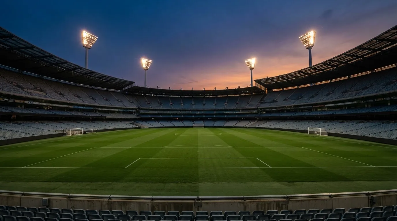 Een leeg voetbalstadion met lichtmasten bij schemering