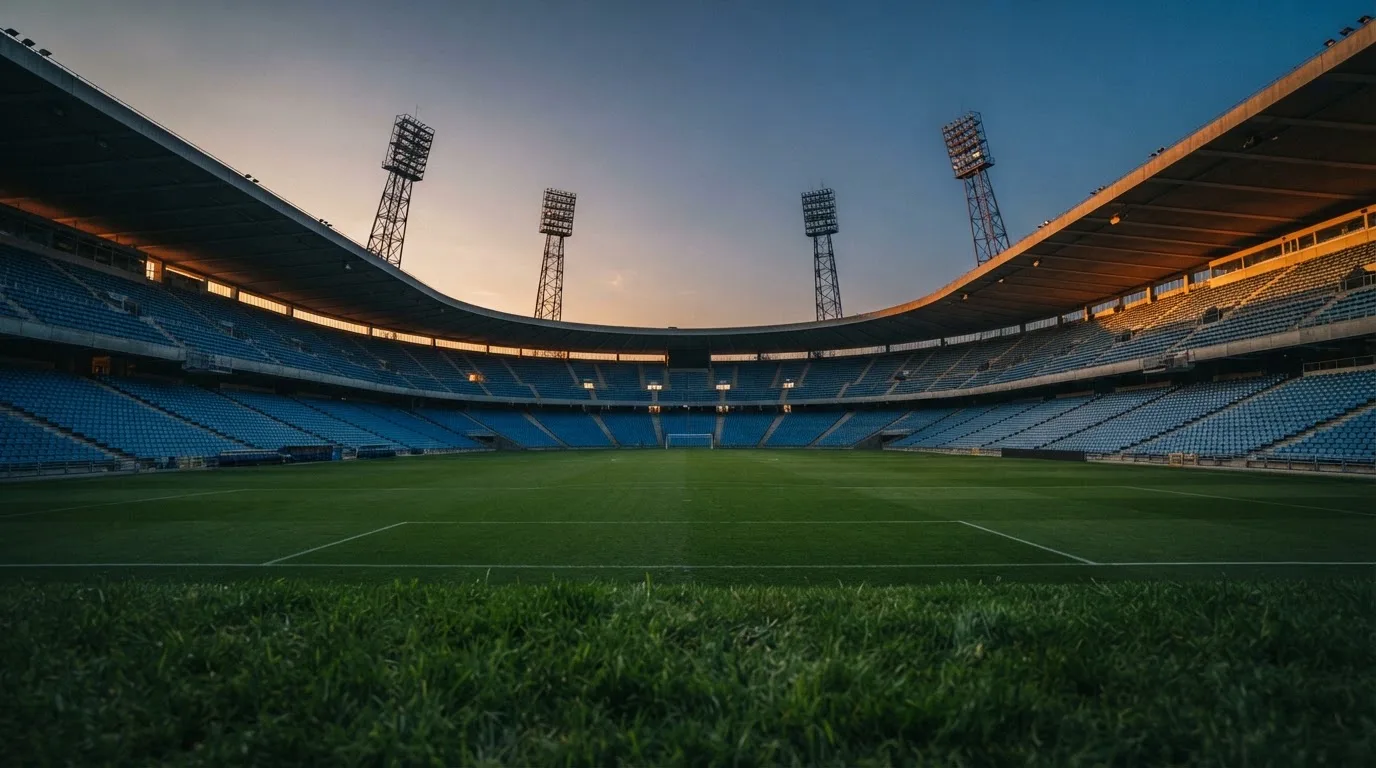 Een leeg voetbalstadion met lichtmasten bij schemering