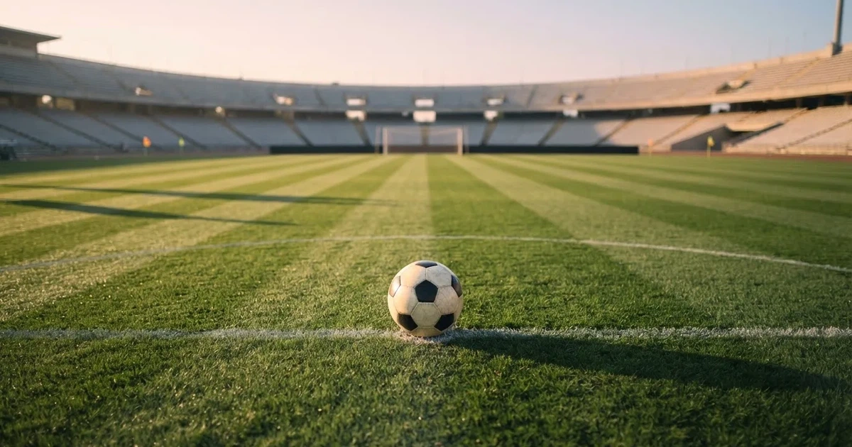 Een voetbal op de middenstip van een grasveld in het ochtendlicht