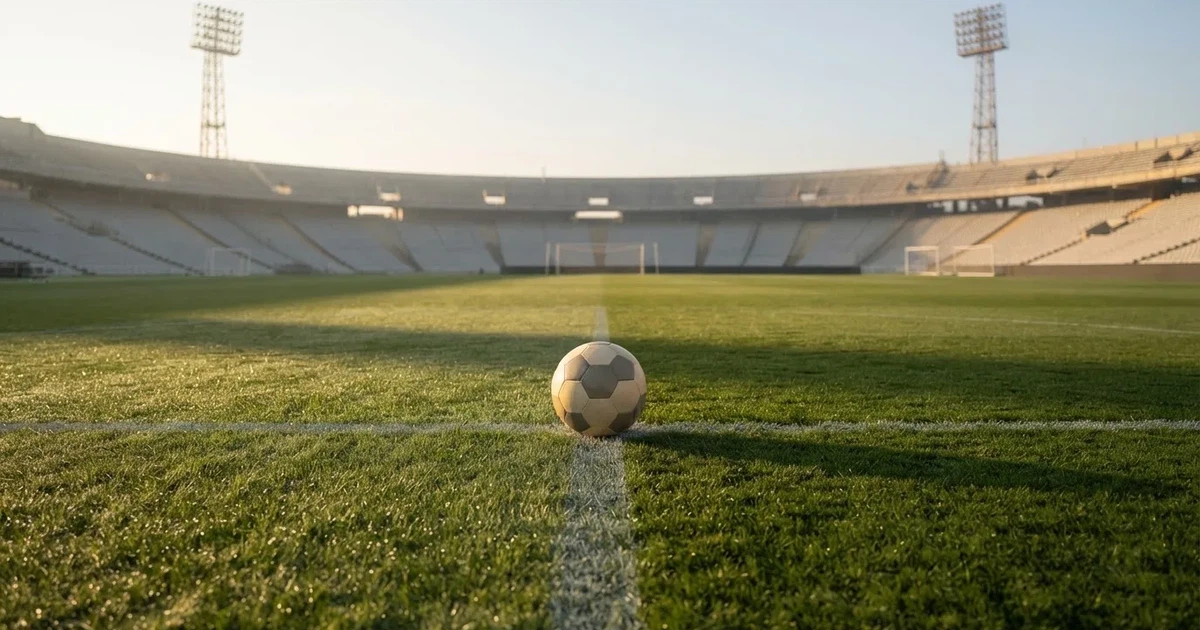 Een voetbal op de middenstip van een grasveld in het ochtendlicht
